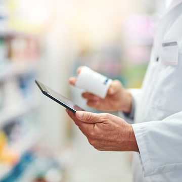 Profesional de farmacia consultando medicamentos en una tablet